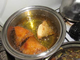 Fried samosas browning in the pot